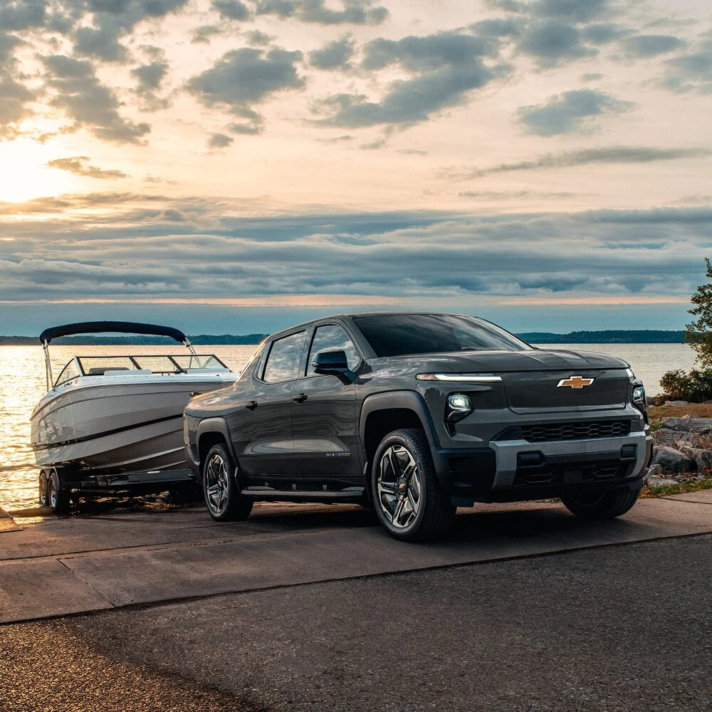 Chevrolet Silverado EV with a boat trailer beside the water